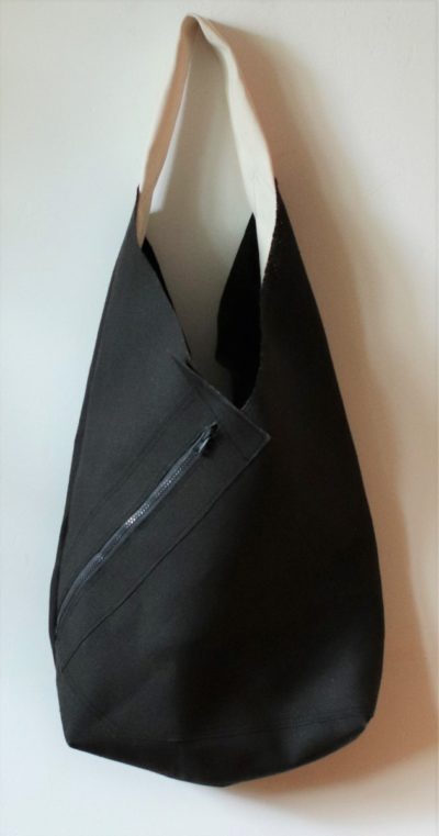 Torba z papieru - kolekcja Origami City torba lniana z grubego czarnego brezentu lnianego o wydłużonym kształcie. Otwarta, na szerokim pasku na ramię, z charakterystyczną kieszenią zewnętrzną "na ukos" zapinaną na zamek.